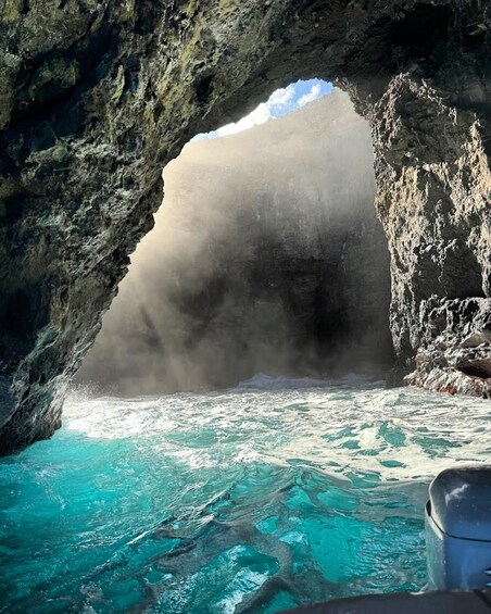 A rocky cave entrance with turquoise water below. 5