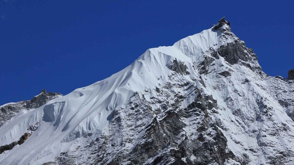 A snow-covered mountain peak with a clear blue sky. 5