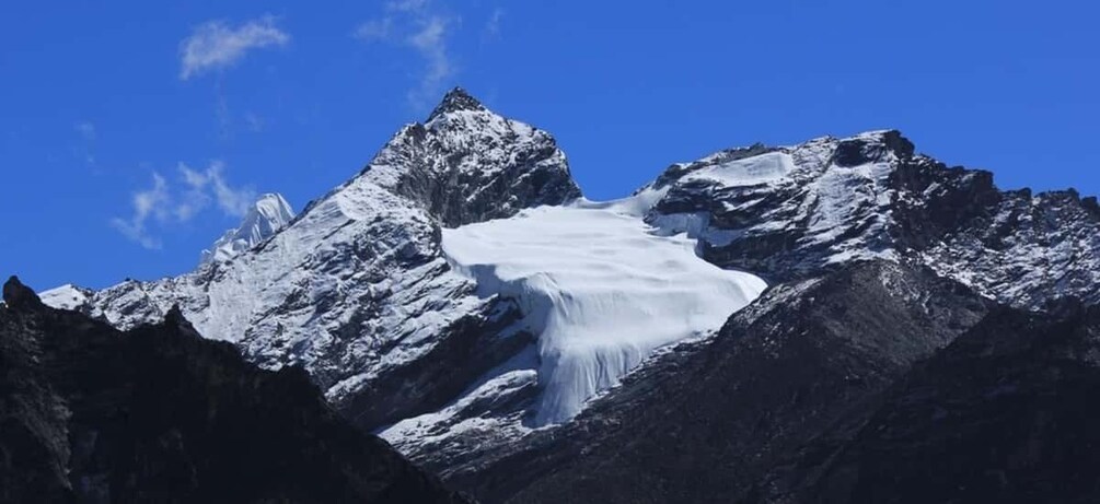 A glacier in a mountainous landscape with sharp peaks and a clear blue sky. 2