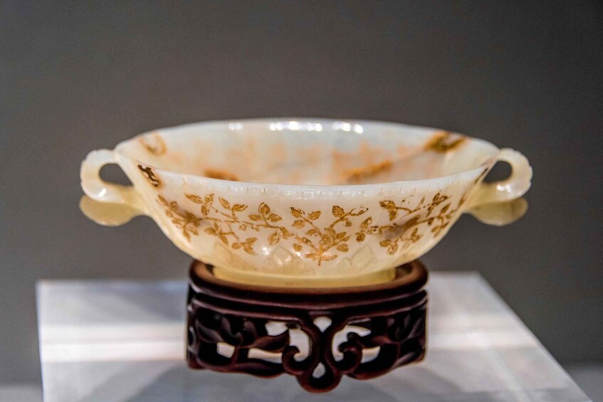 A white ceramic bowl with gold floral patterns, placed on a dark wooden stand. 5
