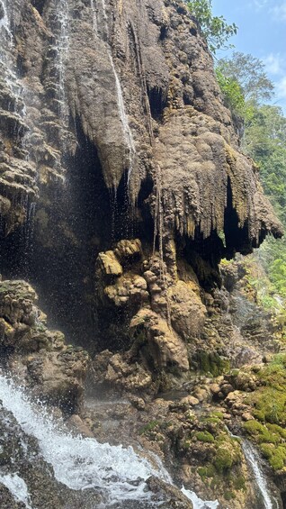 A waterfall cascading down a rocky cliff surrounded by greenery. 5