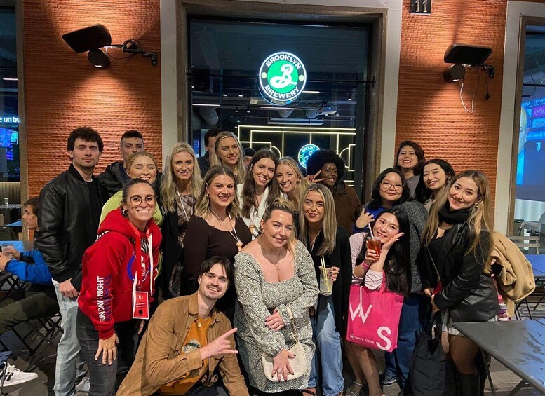 A group of people posing in front of a brick building with a neon sign that reads "Brooklyn Brewery". 1