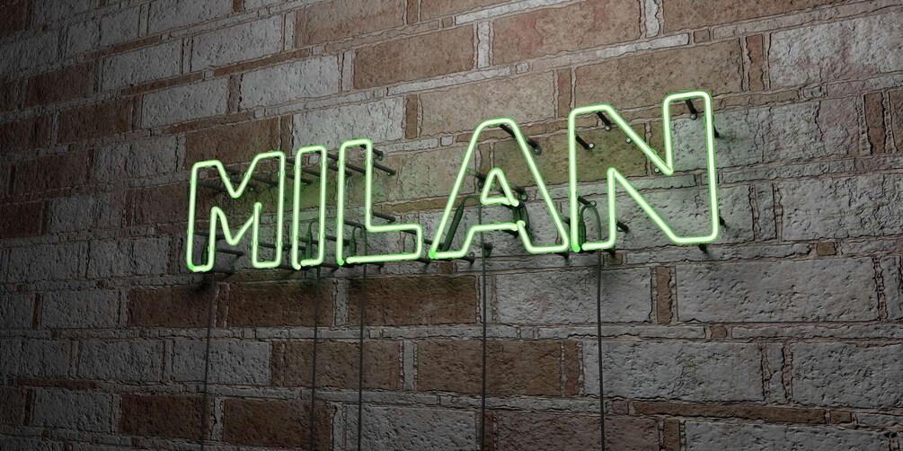 A neon sign spelling "MILAN" on a brick wall. 4