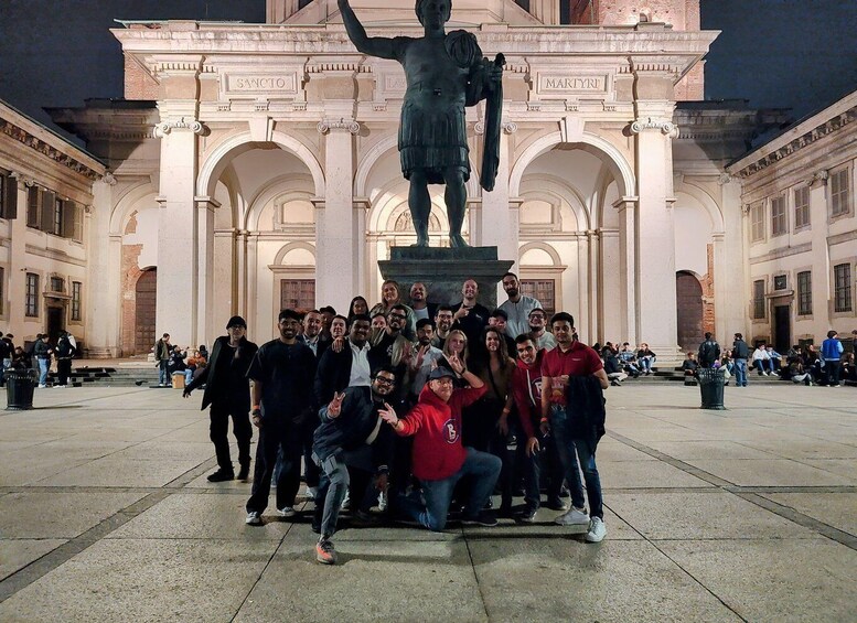 A group of people posing in front of a statue in a plaza with classical architecture. 3