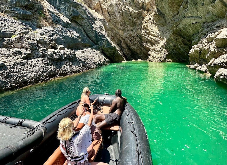 A group of people on a raft in a clear green river surrounded by rocky cliffs. 1