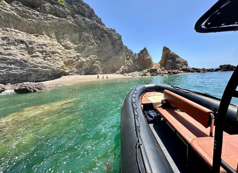 A clear turquoise sea, rocky cliffs, and a sandy beach. 2