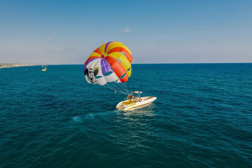 A parasailer with a colorful parachute over a speedboat on the water. 3