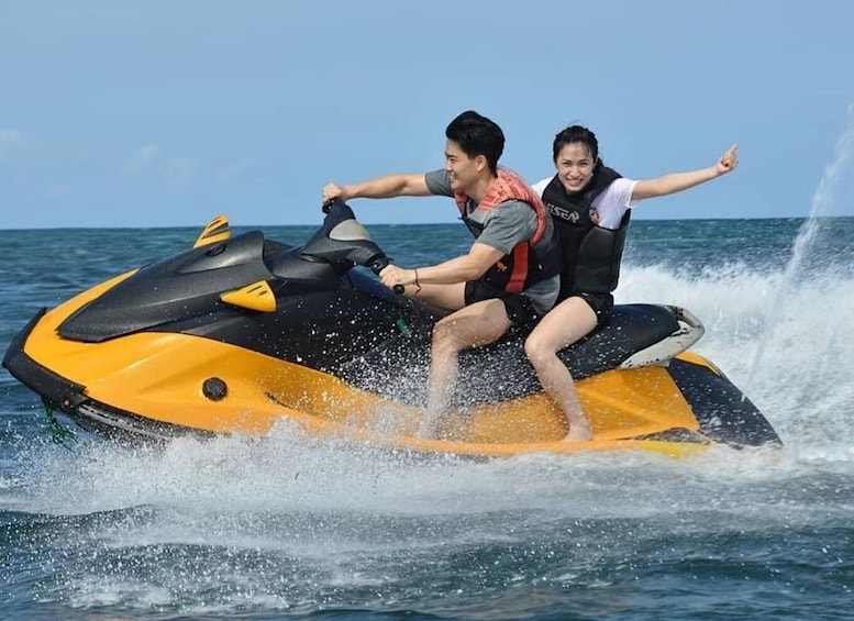 Two people on a yellow and black jet ski in the ocean. 2