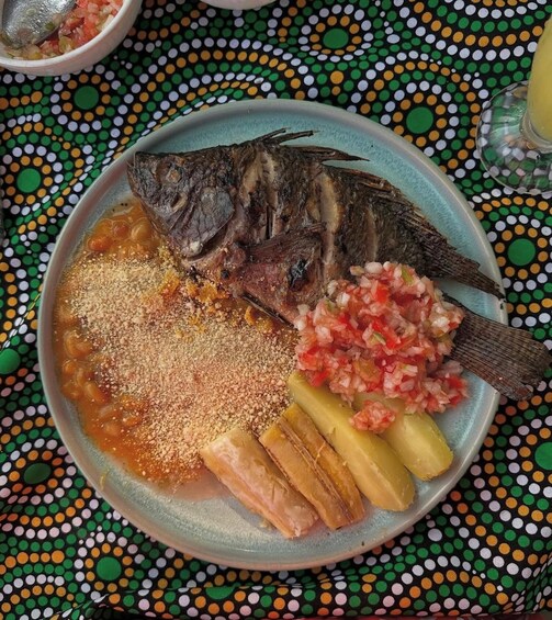 A plate with a whole fish, a side of pickled vegetables, and a bowl of sauce. 5