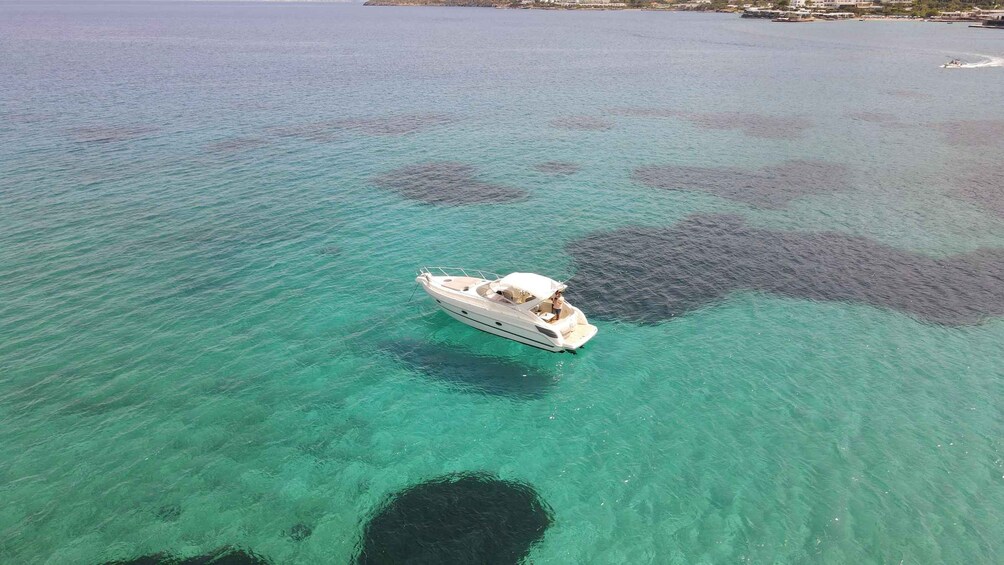 A boat on clear turquoise water with a small island in the background. 5