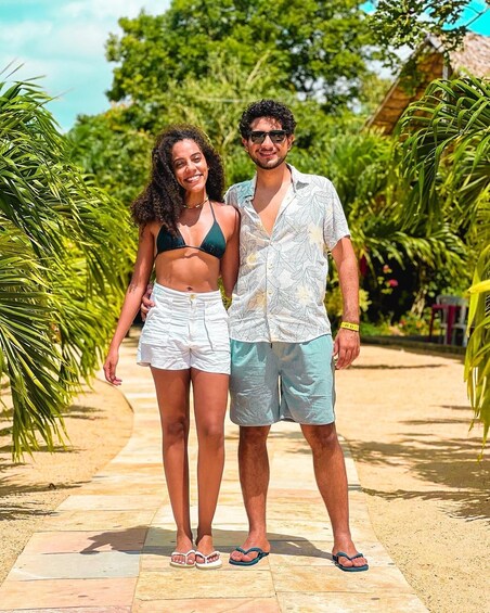 Two people standing on a paved path surrounded by lush greenery. 2