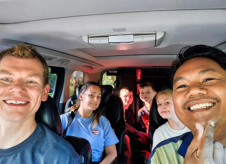 A group of people inside a vehicle with a visible rearview mirror and a window. 2