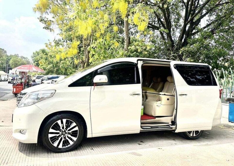 A white minivan parked on a paved area with trees in the background. 4