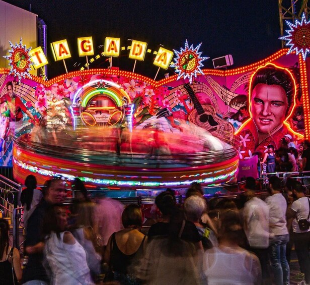 A vibrant amusement ride with the word 'TAGADA' illuminated in neon lights. 2