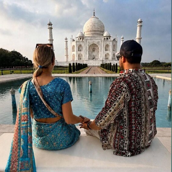Two people sitting by a reflective pool with the Taj Mahal in the background. 2