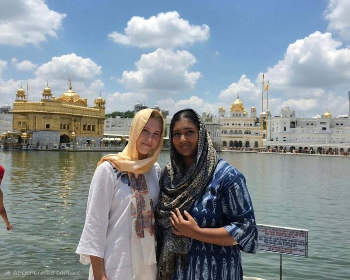 Two people standing by a body of water with a golden temple and white buildings in the background. 2