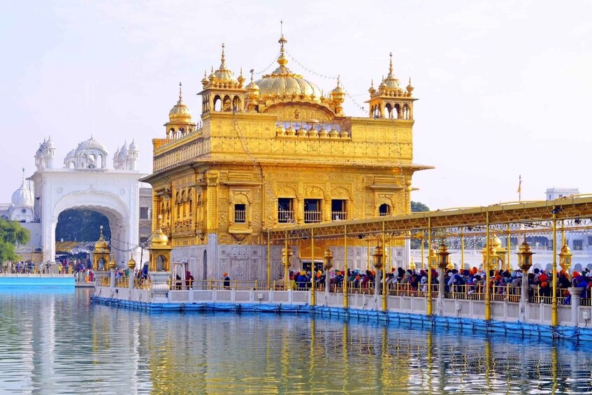 The Golden Temple with a reflection in the water, surrounded by a bridge and visitors. 1