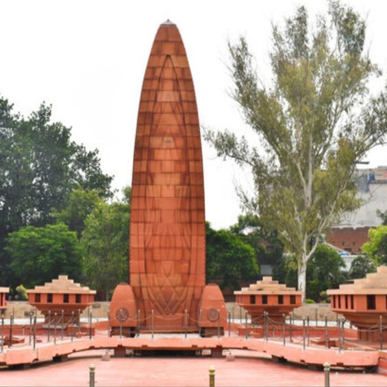 A tall, slender monument with intricate carvings, surrounded by smaller structures and a paved area. 2