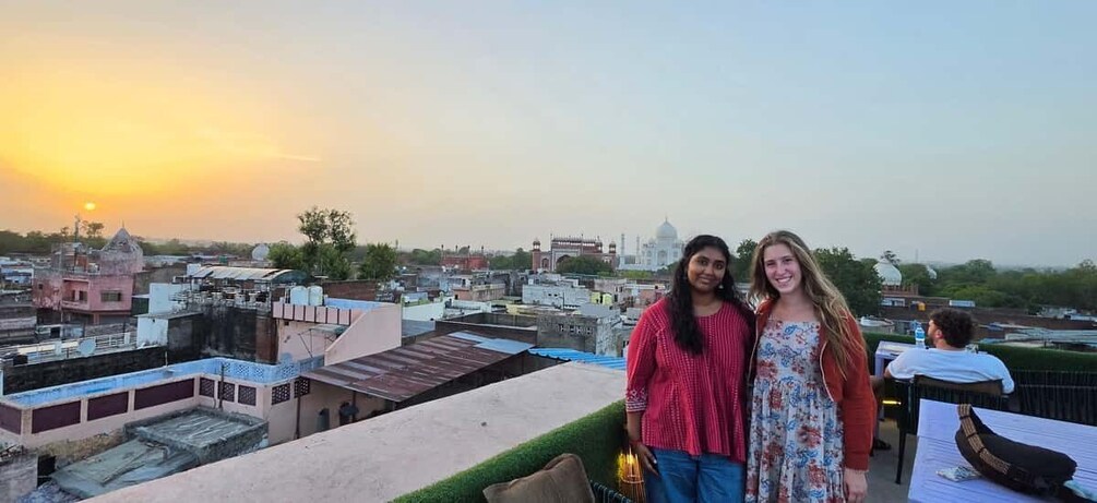 Two people on a rooftop with a cityscape and a prominent dome in the background. 3