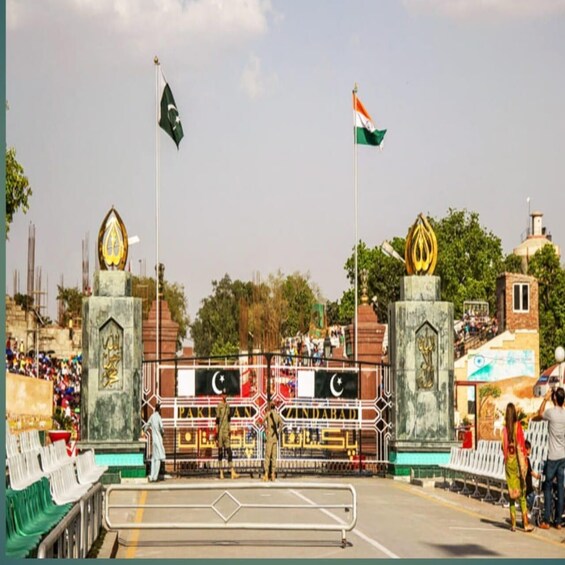 A gate with flags, a monument, and a crowd of people. 3