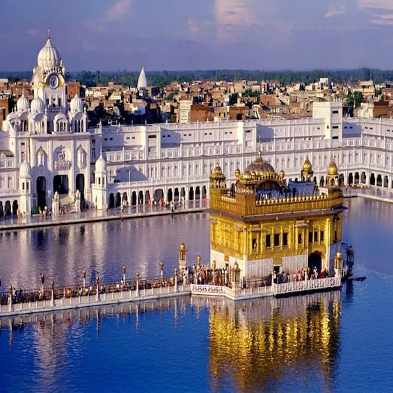 The Golden Temple in Amritsar, surrounded by a large body of water, with a white temple complex in the background. 4