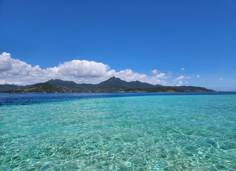 A clear blue sea with a mountain range in the background. 1
