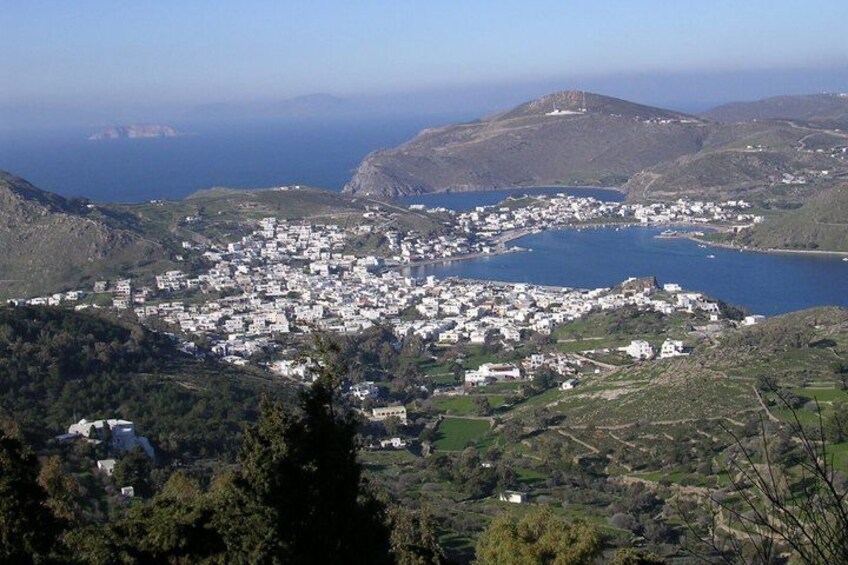 A coastal town with white buildings, surrounded by hills and a large body of water. 1