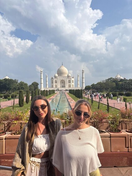 Two people standing in front of the Taj Mahal with a clear sky. 5