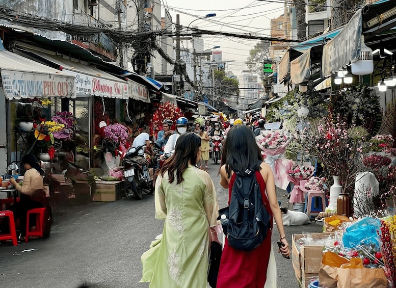 A bustling street market with various stalls selling flowers and goods. 2