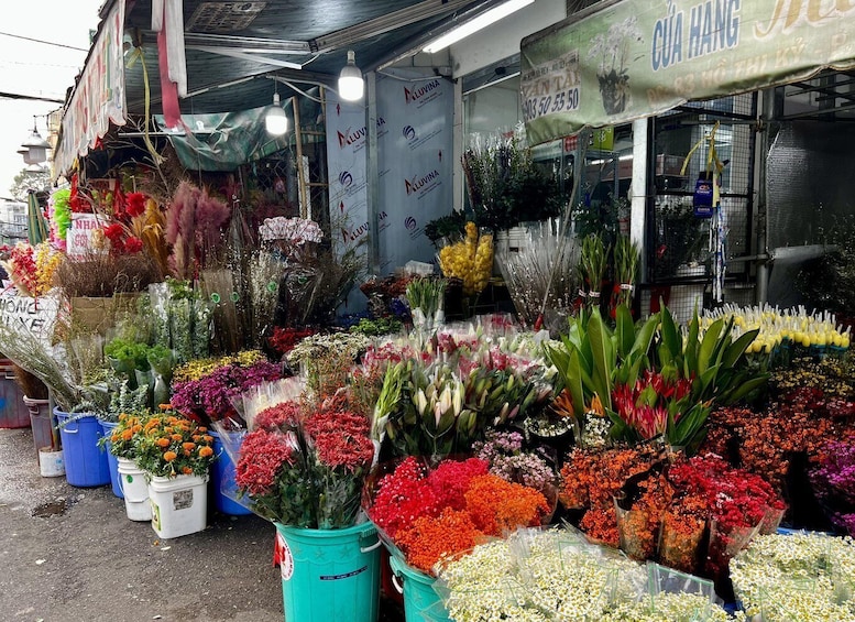 A flower market stall with various colorful flowers and plants displayed in buckets and pots. 3