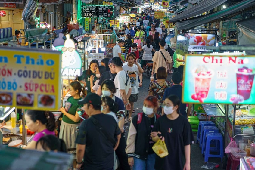 A crowded street market with people walking and vendors selling goods. 4