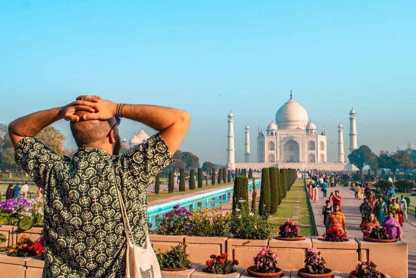 A person taking a photo of the Taj Mahal with a garden in the foreground. 4