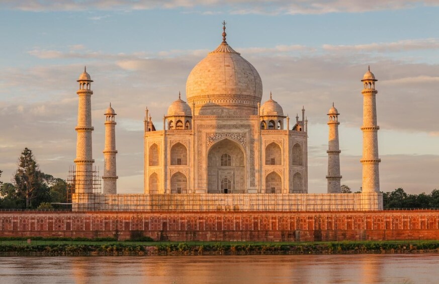 The Taj Mahal with four minarets and a large central dome, surrounded by a red wall and a river. 5