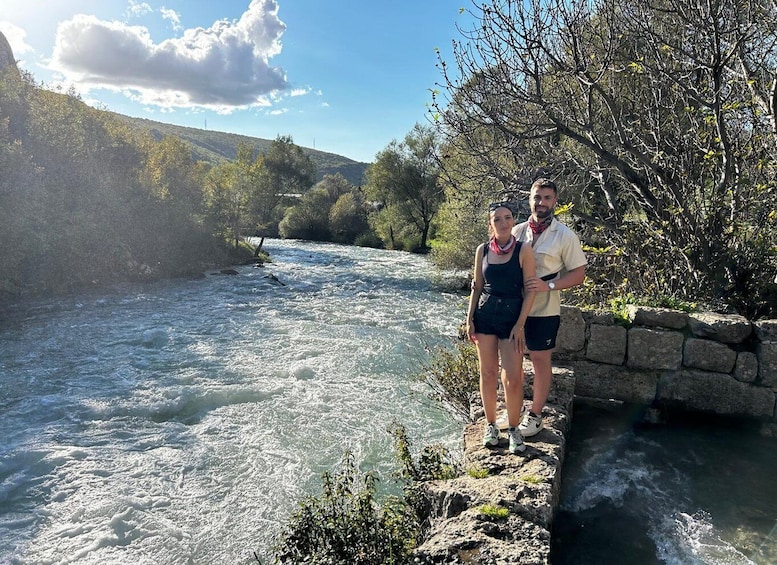 A river with flowing water, a stone wall, and trees in the background. 4