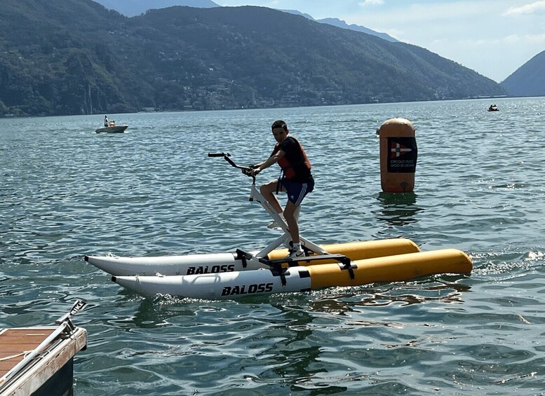 A person riding a paddleboard on water with mountains in the background. 2