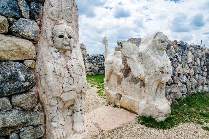 Ancient stone carvings of figures and a stone wall. 5