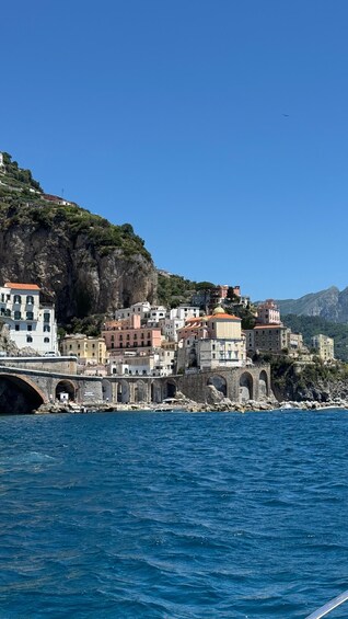 Une ville côtière aux bâtiments aux couleurs vives, avec un pont de pierre et une mer d’un bleu limpide. 2
