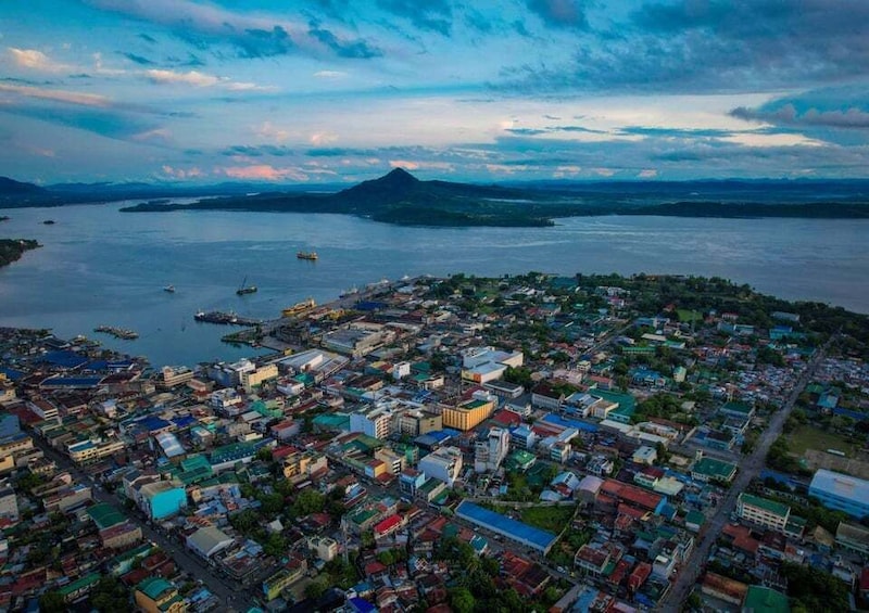 An aerial view of a coastal city with a dense urban area, a large body of water, and a distant mountain. 3
