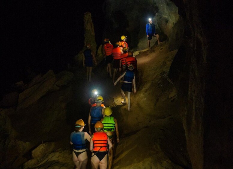 A group of people hiking in a rocky cave at night. 1