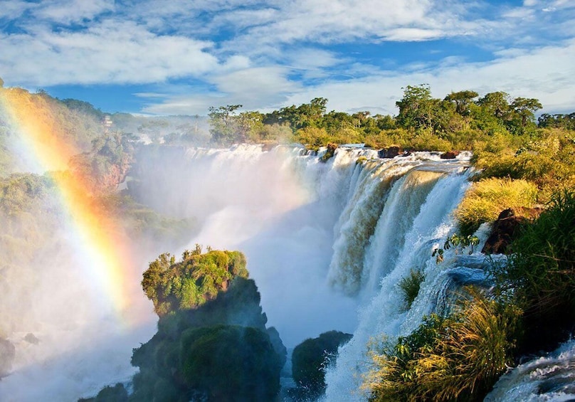 A waterfall with a rainbow, surrounded by lush greenery. 5