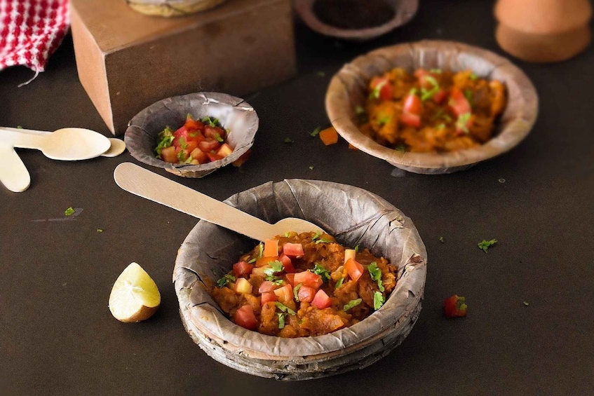 Three bowls of food with a wooden spoon, a lemon half, and a red and white checkered cloth in the background. 1