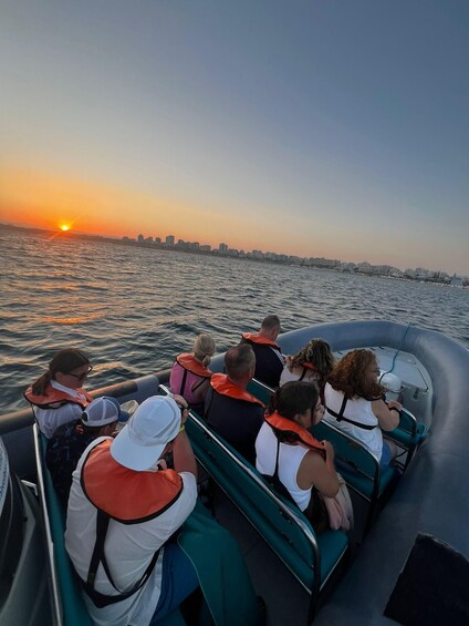 People on a boat with life jackets, enjoying a sunset over water. 5
