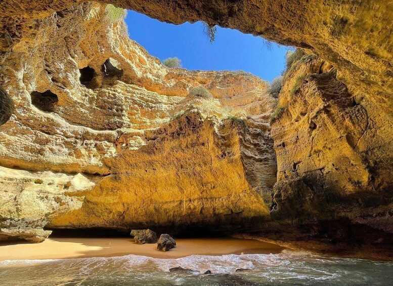 A coastal cave with yellowish rock formations and a sandy beach. 3