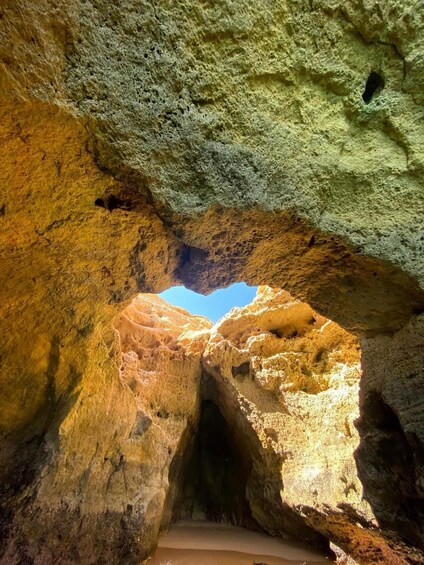 A cave entrance with a natural archway and a clear blue sky visible through the opening. 2
