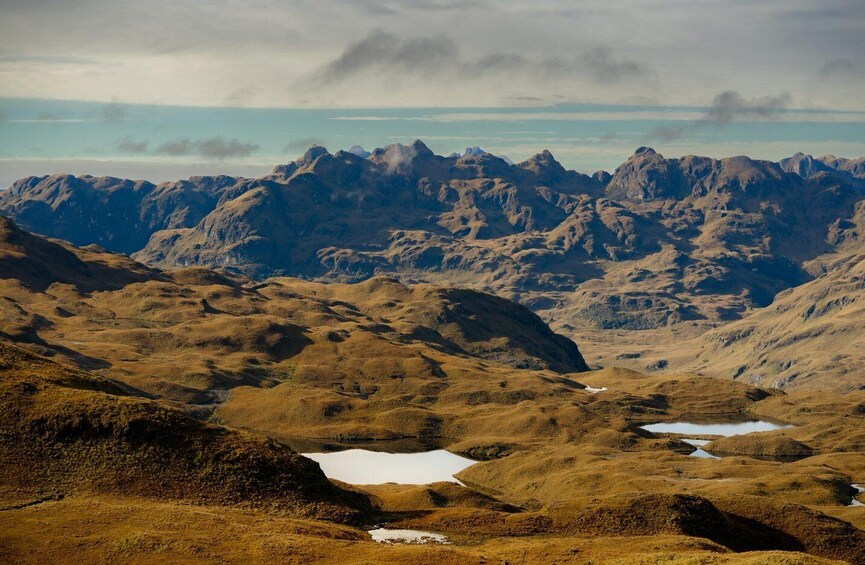 A mountainous landscape with rugged terrain and scattered ponds. 1