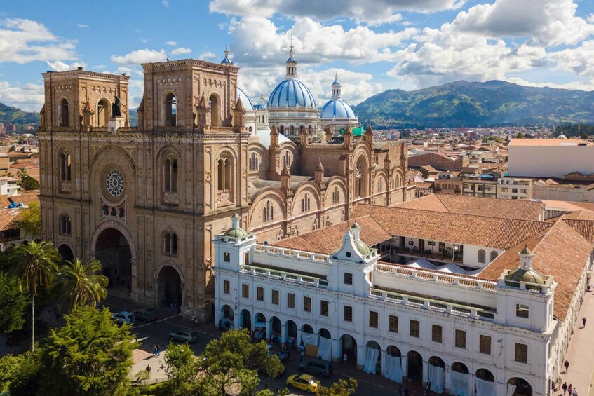 A historic cathedral with a large dome and bell towers, surrounded by a cityscape and mountains. 3