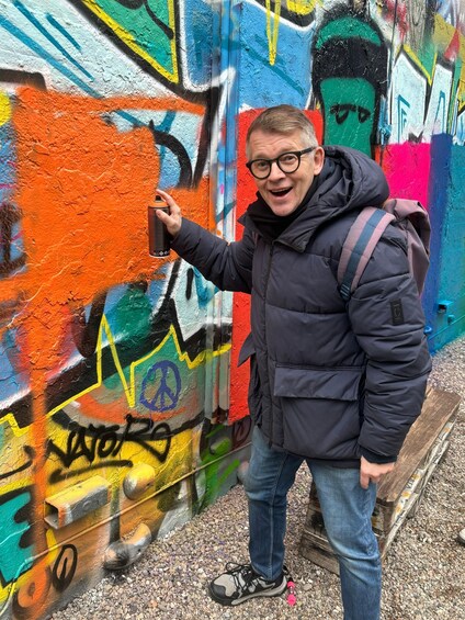 A person pointing at a colorful graffiti wall. 2