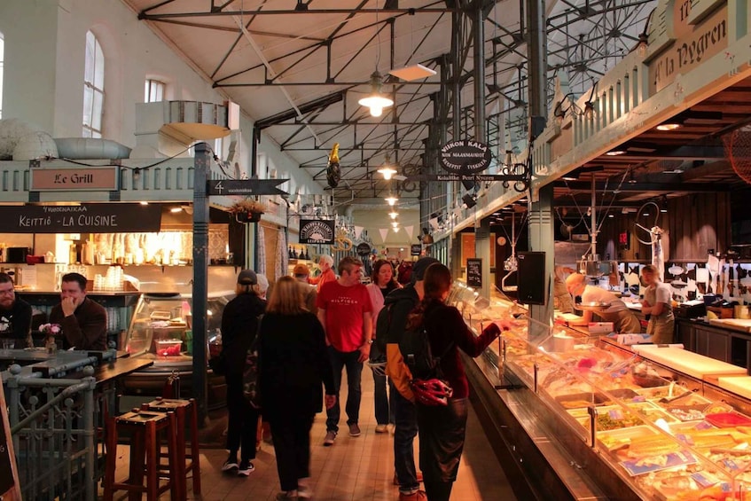A busy indoor market with people walking and food stalls. 4