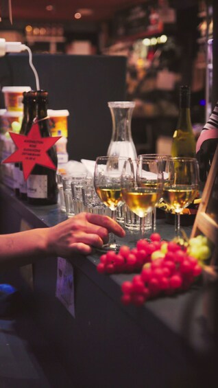 A bar counter with several wine glasses filled with white wine, a bottle of wine, and a red star-shaped sign. 5