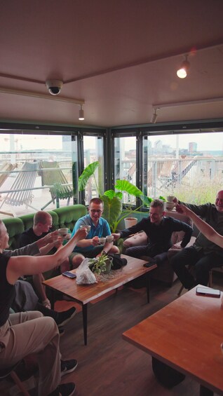 A group of people sitting around a table in a room with large windows, enjoying a meal together. 3